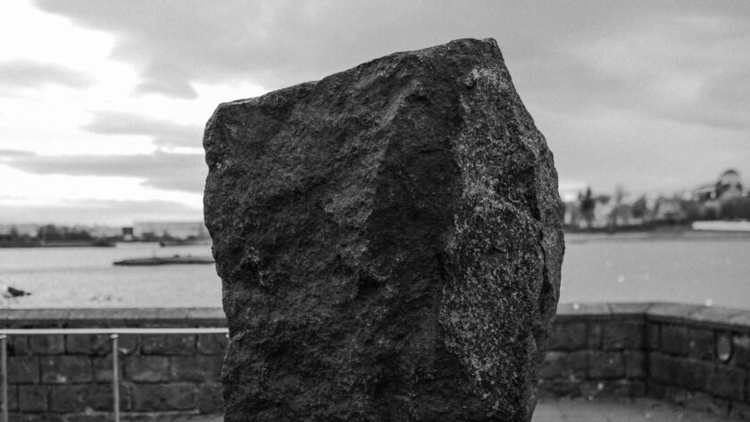 vertical-greyscale-conceptual-shot-rock-headed-person-carrying-bag-concept-dept