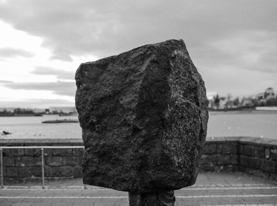 vertical-greyscale-conceptual-shot-rock-headed-person-carrying-bag-concept-dept